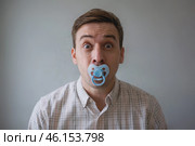 Man with a surprised face sucks a baby's pacifier. Стоковое AI-изображение, AI-художник Дмитрий Киселёв / Фотобанк Лори