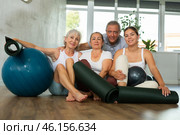 Happy portrait of group of four people with mats and soft balls going to do yoga in gym. Стоковое фото, фотограф Яков Филимонов / Фотобанк Лори