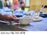 A volunteer's hand holds a cup of soup to distribute free food to hungry people. Стоковое фото, фотограф Darya Komarova / Фотобанк Лори