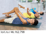 Mom, grandmother and teen grandson do preparatory stretching, lying on back and benting leg at knee. Стоковое фото, фотограф Яков Филимонов / Фотобанк Лори