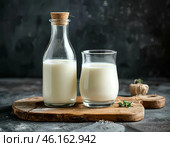 Органическое натуральное коровье молоко в стеклянной бутылке и стакане на стильной деревянной доске на каменном столе. Натуральные экологически чистые продукты. Стоковое AI-изображение, AI-художник Руслан Лесков / Фотобанк Лори