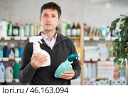 Among shop windows, man buyer leisurely examines goods and chooses glass cleaner spray. Стоковое фото, фотограф Яков Филимонов / Фотобанк Лори