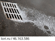 Решетка водостока и черный отпечаток ботинка на присыпанном снегом асфальте. Стоковое фото, фотограф Наталья Николаева / Фотобанк Лори