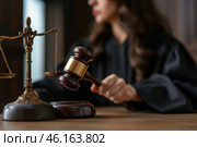 A female judge holding a gavel while presiding over a trial in a historic courtroom setting. Стоковое AI-изображение, AI-художник Sergey Grishin / Фотобанк Лори