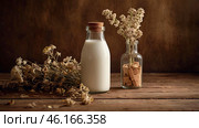 Organic natural oat milk in a glass bottle on a stylish wooden board and plants. Natural, environmentally friendly products. Стоковое AI-изображение, AI-художник Photojuli / Фотобанк Лори