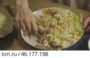 The chef prepares a substantial portion of a seafood salad, blending vegetables and fish on a platter. Стоковое видео, видеограф Strunov David / Фотобанк Лори