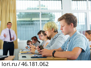 Teenage students using smartphones during lesson. Стоковое фото, фотограф Яков Филимонов / Фотобанк Лори