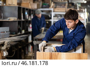 Young worker assembles a wooden table in furniture factory. Work process. Стоковое фото, фотограф Яков Филимонов / Фотобанк Лори