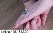 A woman puts a ring with a large transparent stone on her finger. She examines it and shows it off. Close-up. Стоковое видео, видеограф Vadzim Yakubovich / Фотобанк Лори