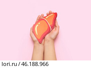 Female hands holding orange paper liver on pink background. Стоковое фото, фотограф Pixel_shot / Фотобанк Лори
