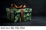 The concept of Defender of the Fatherland Day on February 23. Gift camouflage box with a festive satin ribbon bow on a dark green background. Стоковое AI-изображение, AI-художник Photojuli / Фотобанк Лори