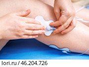 Hands attaching an electrode from an electrical muscle stimulator to a leg, demonstrating the application of EMS technology for muscle training and rehabilitation. Стоковое фото, фотограф Татьяна Степанищева / Фотобанк Лори