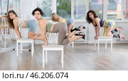 Woman sitting on knees on chair performs lap dance. Female students repeat erotic movements. Стоковое фото, фотограф Яков Филимонов / Фотобанк Лори