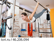 Girl practicing advanced aerial Pilates pose on trapeze bar. Стоковое фото, фотограф Яков Филимонов / Фотобанк Лори