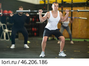 Determined young guy working out with weight rod during crossfit workout. Стоковое фото, фотограф Яков Филимонов / Фотобанк Лори
