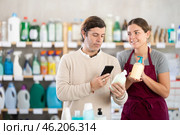 Female salesperson offers to buy a liquid hand soap while a man checks a QR code using smartphone. Стоковое фото, фотограф Яков Филимонов / Фотобанк Лори