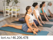 Girl stretching in seated asana Ardha Kapotasana at group yoga session. Стоковое фото, фотограф Яков Филимонов / Фотобанк Лори
