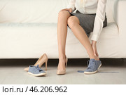 Tired young woman changing shoes indoors. Стоковое фото, фотограф Pixel_shot / Фотобанк Лори
