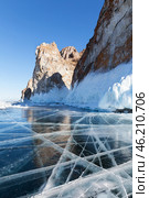 Baikal Lake in sunny cold February day. View of natural landmark of Olkhon Island - famous Cape Sagan-Khushun or Three Brothers Rocks from blue clear ice with cracks. Beautiful winter landscape. Стоковое фото, фотограф Виктория Катьянова / Фотобанк Лори