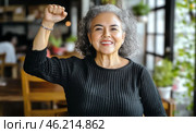 Middle aged hispanic woman with raised fist of empowerment, strength and women solidarity, International Womens Day concept. Стоковое AI-изображение, AI-художник Анастасия Золотницкая / Фотобанк Лори