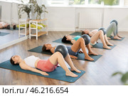 Together with students, she lies on mat, holds fitball between knees and raises and lowers buttocks. Стоковое фото, фотограф Яков Филимонов / Фотобанк Лори