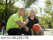 Two basketball players sitting on bench and discussing game on sports court. Outdoor workout. Стоковое фото, фотограф Светлана Лажко / Фотобанк Лори