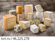 Various types of cheese front view. Assortment of different types of cheese on rustic wooden table. Cheeses selection. Dark old wood background, copy space. Variety of french cheese, pieces and whole. Стоковое AI-изображение, AI-художник Марина Демидюк / Фотобанк Лори