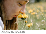Young woman smells a wildflower in summer. Стоковое AI-изображение, AI-художник Дмитрий Киселёв / Фотобанк Лори
