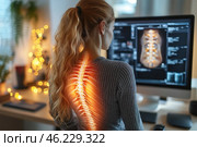 A young woman with long blonde hair pulled back into a ponytail sits at a computer wearing a dark sweater. She is working with medical images of a spine on the monitor screen. The visualization of the spine is superimposed on her back, creating the effect of an x-ray with an orange glow. The atmosphere in the room is cozy, with warm lighting and fairy lights in the background. The image symbolizes problems with posture, back pain, or work in the medical field. Стоковое AI-изображение, AI-художник Анна Кривицкая / Фотобанк Лори