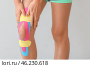 Sporty woman with physio tape applied on knee against light background, closeup. Стоковое фото, фотограф Pixel_shot / Фотобанк Лори