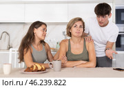 Sad mom sits silently in kitchen, adult children, guy and girl sympathize and comfort woman. Стоковое фото, фотограф Яков Филимонов / Фотобанк Лори