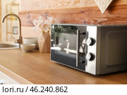 Microwave oven on wooden tabletop in kitchen. Стоковое фото, фотограф Pixel_shot / Фотобанк Лори