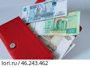 Денежные купюры и красный кошелек на сером фоне. Стоковое фото, фотограф Сергей Овчинников / Фотобанк Лори
