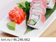Sushi platter with colorful rolls, garnished with ginger, wasabi, and seaweed salad on a white plate. Стоковое фото, фотограф Сергей Толмачёв / Фотобанк Лори