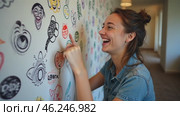 Woman is pointing at a wall with a lot of drawings on it. Стоковое AI-видео, аниматор Sergey Grishin / Фотобанк Лори