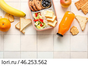 Lunchboxes with delicious food and bottle of juice on white tile background. Стоковое фото, фотограф Pixel_shot / Фотобанк Лори