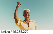 Black mature woman outdoors with raised fist of empowerment, strength and women solidarity, International Womens Day, Black History Month concept. Стоковое AI-изображение, AI-художник Анастасия Золотницкая / Фотобанк Лори