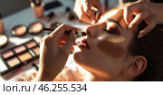 Makeup artist applies bronzer on woman's face during a beauty session in a well-lit workspace in the afternoon. Стоковое AI-изображение, AI-художник Сергей Толмачёв / Фотобанк Лори