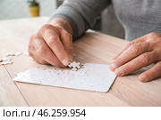 Senior man with Parkinson syndrome doing puzzle at home, closeup. Стоковое фото, фотограф Pixel_shot / Фотобанк Лори