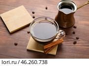 Drink coasters with cup of coffee, cinnamon and jezve on wooden table. Стоковое фото, фотограф Pixel_shot / Фотобанк Лори