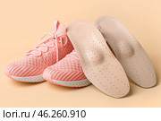 Orthopedic insoles and sneakers on beige background. Стоковое фото, фотограф Pixel_shot / Фотобанк Лори