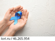 Woman holding blue ribbon on light background. Cancer concept. Стоковое фото, фотограф Pixel_shot / Фотобанк Лори