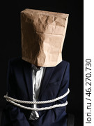 Male hostage with paper bag on dark background. Стоковое фото, фотограф Pixel_shot / Фотобанк Лори