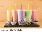Board with plastic cups of different tasty bubble tea on table. Стоковое фото, фотограф Pixel_shot / Фотобанк Лори