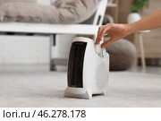 Woman adjusting electric fan heater in living room, closeup. Стоковое фото, фотограф Pixel_shot / Фотобанк Лори