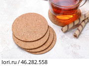 Drink coasters with cup of tea and wafer rolls on white table. Стоковое фото, фотограф Pixel_shot / Фотобанк Лори