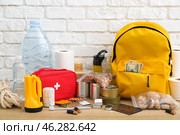 Necessities for emergency bag on wooden table near white brick wall. Стоковое фото, фотограф Pixel_shot / Фотобанк Лори