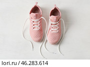 Pair of sportive shoes with untied laces on light wooden background. Стоковое фото, фотограф Pixel_shot / Фотобанк Лори