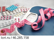 Weight loss pills, scales and measuring tape on grey background. Стоковое фото, фотограф Pixel_shot / Фотобанк Лори