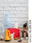 Necessities for emergency bag on wooden table near white brick wall. Стоковое фото, фотограф Pixel_shot / Фотобанк Лори